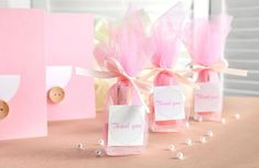 three small bottles with pink flowers in them on a table next to two greeting cards