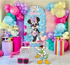 a birthday party with balloons, decorations and mickey mouse character on the table in front of it