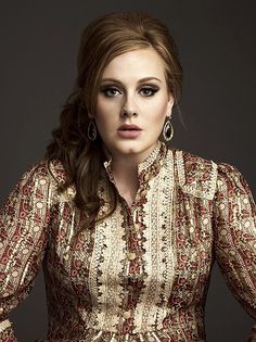 a woman with long hair wearing a brown and white dress is posing for a photo