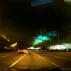 the view from inside a car at night time, with lights and signs in the background