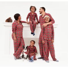 three adults and two children in matching red plaid pajamas with a dog on the floor