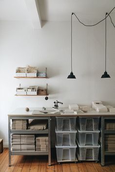 a desk with several bins on top of it and hanging lights above the desk