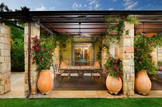 an outdoor dining area with large vases and flowers