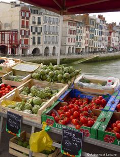 an open air market with lots of vegetables and fruits for sale on the side of the river