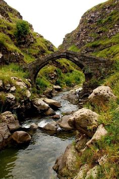 a stone bridge over a small stream in the mountains