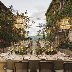 an outdoor dining table set up with candles, plates and place settings for two people