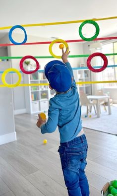 a toddler is playing with some balls in the living room while wearing a blue hoodie