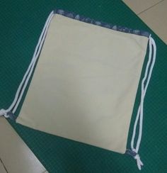 a drawstring bag sitting on top of a green mat next to a pair of scissors