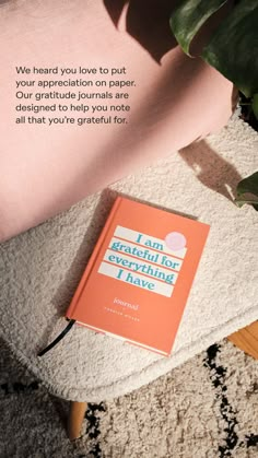 an orange book sitting on top of a white rug next to a potted plant