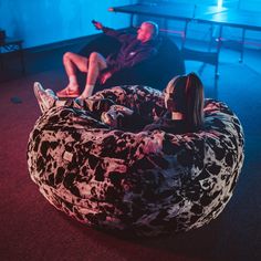 two people sitting on bean bag chairs in a room