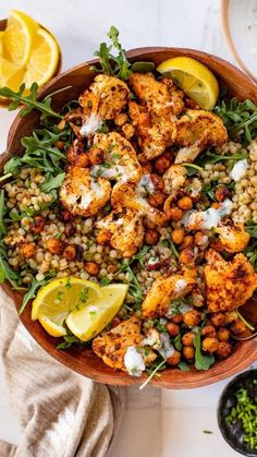 a bowl filled with chickpeas, spinach and lemon wedges on top of a table