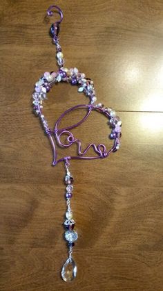 a beaded necklace with the word love hanging from it's side on a wooden table