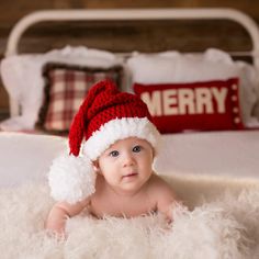 a baby wearing a santa hat on top of a bed