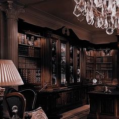 an old fashioned library with chandelier and desk