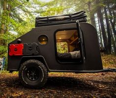 an off - road camper is parked in the woods with its bed pulled up