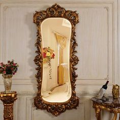 an ornate gold framed mirror in the corner of a room with flowers and vases