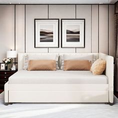 a large white bed sitting under two framed pictures