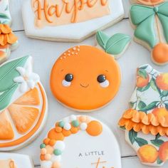 some decorated cookies are sitting on a white table with oranges and other items in the background