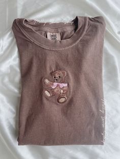 "Embroidered Teddy Bear T-Shirt! -Embroidered on 100% cotton Comfort Colors T-shirt, this design is simple and minimalistic, perfect for every outfit! -Embroidery design measures 2.25\" x 3.5\". -See product pictures for shirt sizing chart. **T-SHIRTS ARE IN UNISEX SIZING AND RUN TRUE TO SIZE. -All t-shirts are handmade on an embroidery machine so there may be slight differences, but we only sell the sweatshirts that meet our high-quality standards. -To maintain the quality of your T-shirt and t Teddy Bear Aesthetic Clothes, Embroidery Designs On Tshirt, Teddy Bear T Shirt, Embroidery Tshirts, Aesthetic Cozy, Embroidered Tee, Sweat Shirts, Bear T Shirt, Embroidered Tshirt