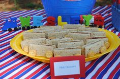 a plate full of sandwiches sitting on top of a red and blue striped table cloth