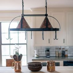 a kitchen island with two hanging lights and bowls on the counter top in front of it