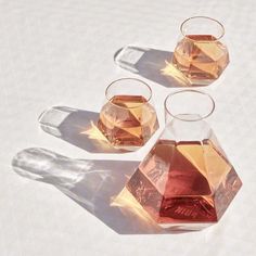 three glass vases filled with liquid on top of a white tablecloth covered floor