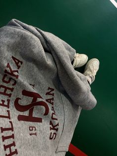 a person standing on top of a tennis court wearing a hoodie and white sneakers