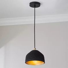 a black lamp hanging from the ceiling in a room with white walls and flooring