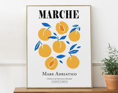 a poster with oranges on it sitting next to a potted plant in front of a white wall