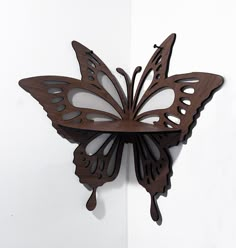 a butterfly shaped clock mounted to the side of a wall next to a white wall