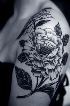 a black and white photo of a woman's shoulder with flowers on it