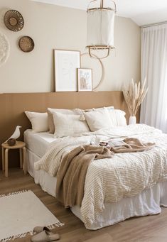 a bed with white linens and pillows in a bedroom next to a wooden floor