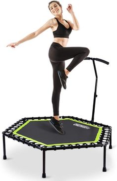 a woman is jumping on a trampoline with her arms in the air and smiling