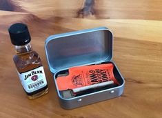 an open tin can with some liquor in it next to a bottle on a wooden table