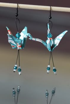 two small blue birds hanging from hooks