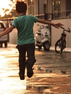 a young boy is running in the rain