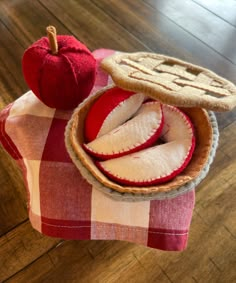 an apple pie and two slices are on a red checkered cloth with a wooden floor