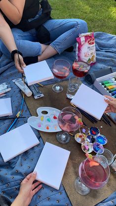 people sitting on the ground painting with watercolors and paintbrushes in front of them