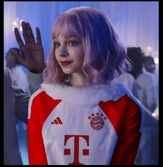 a woman with pink hair wearing a red and white soccer uniform waves to the crowd