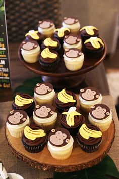 cupcakes with chocolate frosting and banana decorations on a wooden plate next to a sign