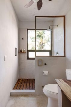 a bathroom with a ceiling fan and wooden flooring