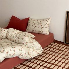 a bed sitting on top of a wooden floor next to a wall with a mirror