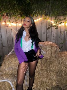 a woman standing in front of hay bales wearing stockings and tights with lights on the fence behind her