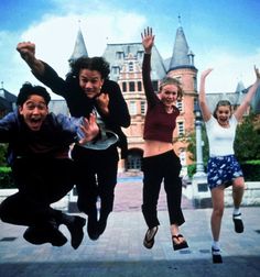 four people jumping in the air with their hands up