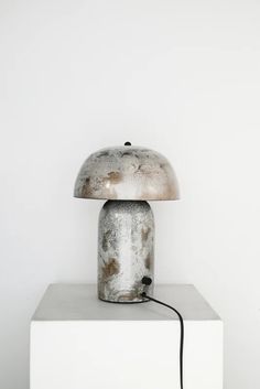 a lamp that is sitting on top of a white block with a black cord attached to it