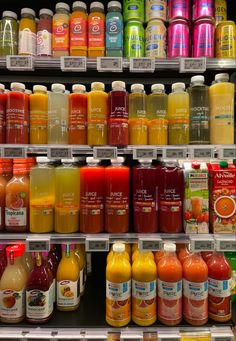 many different types of juices are on display in a grocery store, including orange and yellow