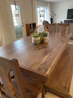 a wooden dining table with two chairs and a basket on it's centerpiece