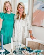 two women standing next to each other in front of a table with place settings on it