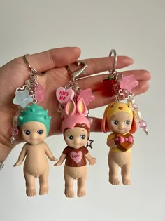 three little doll keychains are being held by someone's hand