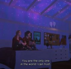 two people sitting on a bed in a room with blue lights and stars above them